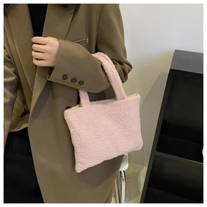 Detailed view of plush pink faux fur handbag being held by a model in a brown blazer