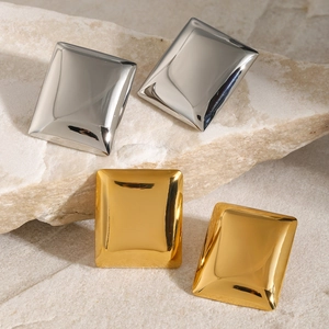 Mirror-polished rectangular earrings in gold and silver set on a textured stone surface
