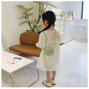 Girl wearing a green crossbody bag with pearl handle and floral charms in a cafe setting