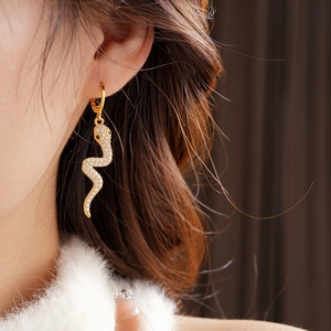 Close-up of gold plated snake-shaped earrings with sparkling cubic zirconia on model