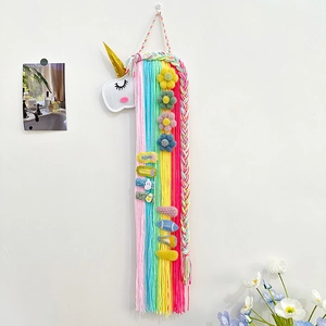 Organisateur de pinces à cheveux licorne en feutre avec pompons colorés sur mur blanc