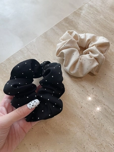 Detail view of knitted ribbed hair scrunchies in black and beige with diamond accents