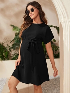 Detail of elegant black maternity dress with short sleeves and waist tie in outdoor setting