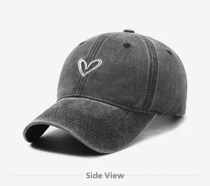 Side view of washed dark grey baseball cap with white heart embroidery and cotton texture