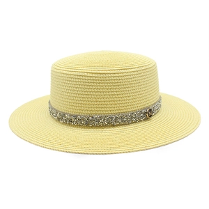 Detail of a straw boater hat with a glitter band and golden M-letter emblem