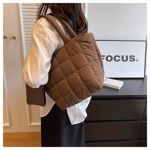 Macro view of brown quilted puffer shoulder bag with soft textured nylon material