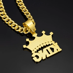Close-up of gold-plated KING crown pendant with shimmering crystals on Cuban link chain