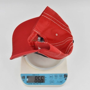 Detailed shot showing a red baseball cap weighing 86.6g on a digital scale for light weight