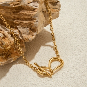 Détail du collier en acier inoxydable 18K avec nœud et fermoir OT sur pierres rustiques