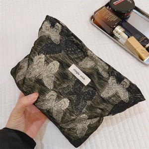 Detail der goldenen Schmetterlingsstickerei auf schwarzer Clutch mit Simple Wish Label