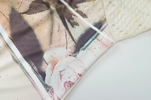 Detail view of pink rose floral print fabric stitched with white lace knit material