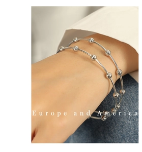 Close-up of a minimalist silver multi-layered stainless steel beaded cuff bracelet