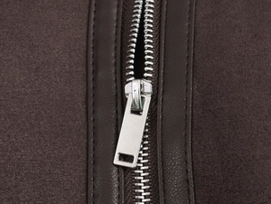 Detailed macro shot of silver metal zipper on brown jacket with faux leather trim