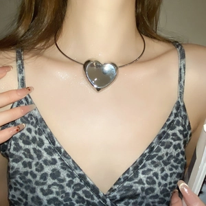 Close-up of model wearing silver heart pendant necklace with metallic finish details