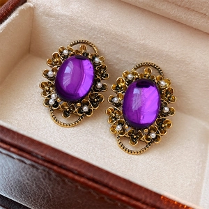 Macro shot of vintage gold earrings with oval purple stones and small white pearls