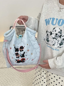 Sac à main bleu clair matelassé avec broderie chat noir et poignées tressées sur modèle