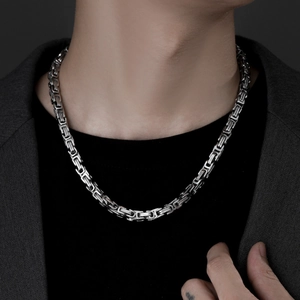 Detail view of a silver Byzantine chain necklace worn on a male model for a street style look