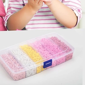 Gros plan d'un enfant utilisant un kit de perles en argile avec perles roses et mauves