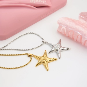 Detailed macro view of 18k gold and silver starfish pendant on twist chain necklace
