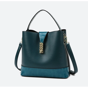 Detail view of dark green bucket bag with crocodile texture trim and gold clasp