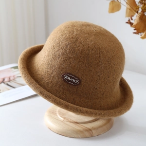 Detail of camel wool felt bucket hat texture with a small side label on a wooden stand