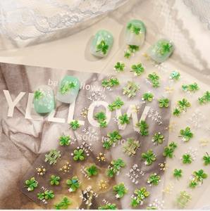Detail of four-leaf clover nail stickers and gradient green press-on nails on magazine