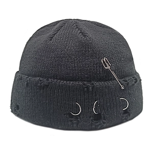 Detail of black distressed knit beanie featuring silver metal rings and safety pin decor