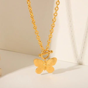 Detailed view of the gold butterfly pendant with OT buckle on a beaded chain necklace
