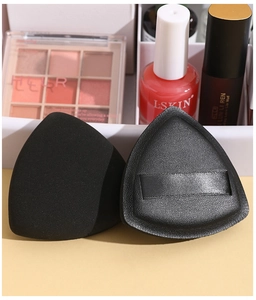Detailed view of two black triangular flocked powder puffs with silky ribbon handles