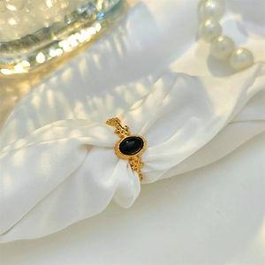 Vintage gold turquoise ring with black oval stone on white silk background