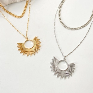 Détail de colliers doubles à pendentif soleil rayonnant en finitions dorée et argentée