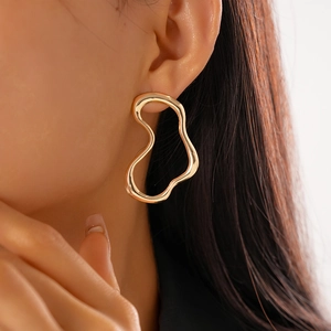 Close-up of irregular geometric gold earrings with a polished metallic finish on a model