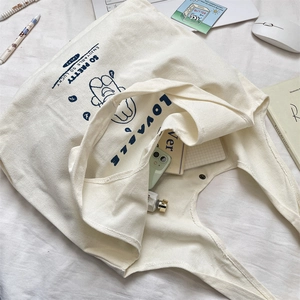 Detailed view of cream canvas tote bag with cute blue dog illustration and stationery