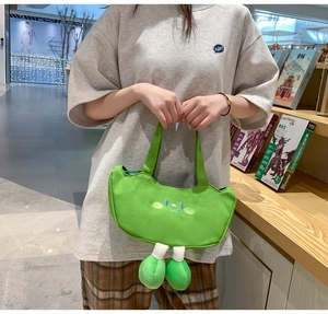Close-up of cute green cartoon canvas tote bag with funny face embroidery and 3D plush legs