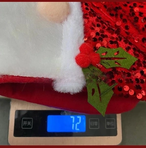 Close-up of a red sequined Christmas stocking with white plush beard and green holly detail