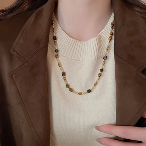 Collier en perles d'œil de tigre porté par un mannequin en blazer brun pour un style élégant