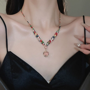 Close-up of pink heart pendant necklace set with colorful zircons on female neck
