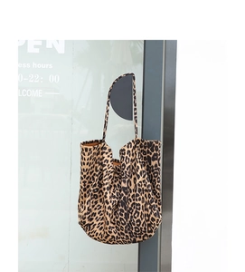 Detail of large leopard print canvas tote bag hanging on a hook against a glass background