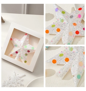 Close-up of white glitter Christmas tree star topper with colorful sequins and packaging