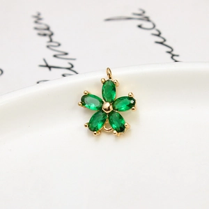 Macro shot of a gold flower pendant with five marquise-cut green zircon petals on ceramic