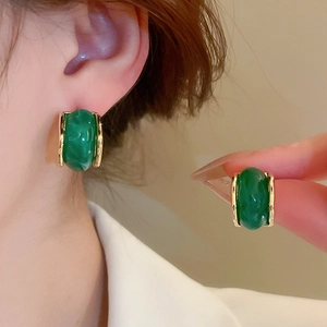 Vue détaillée de boucles d'oreilles en résine marbrée verte avec bordure dorée