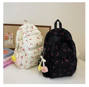 Detail of corduroy texture and cherry embroidery on white and black backpacks