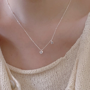 Minimalist 925 sterling silver necklace with star and heart pendants on casual knitwear