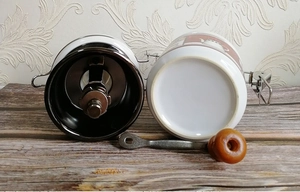 Macro detail of manual coffee grinder components with ceramic jar and wooden handle