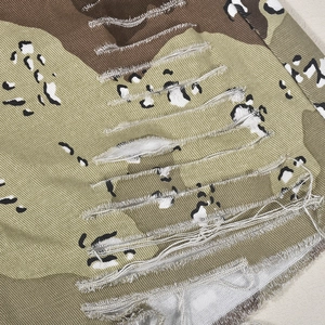 Gros plan du tissu camouflage vieilli avec bords effilochés et texture en sergé