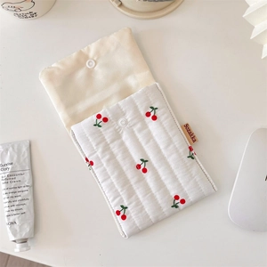 Detail view of quilted cotton pouch with cherry print and side brand label shown with accessories