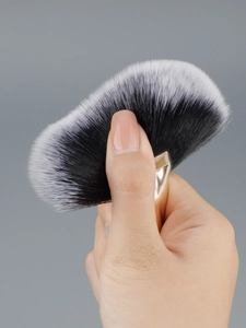 Macro detail of soft fan makeup brush with two-tone bristles and light gold handle