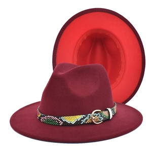 Macro detail of wine red fedora hat featuring snakeskin leather band and gold buckle