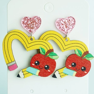 Detailed view of heart-shaped yellow pencil earrings with cute red apple acrylic charm