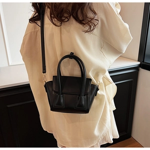 Rear view of a minimalist black leather bucket bag worn by a model in a modern interior